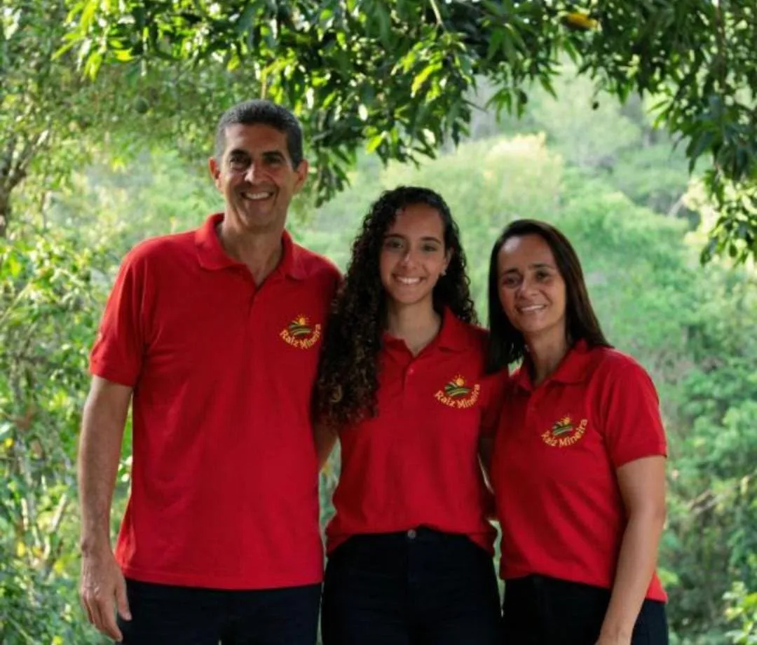 Os três sorrindo num jardim, de camisa vermelha da Raiz Mineira.